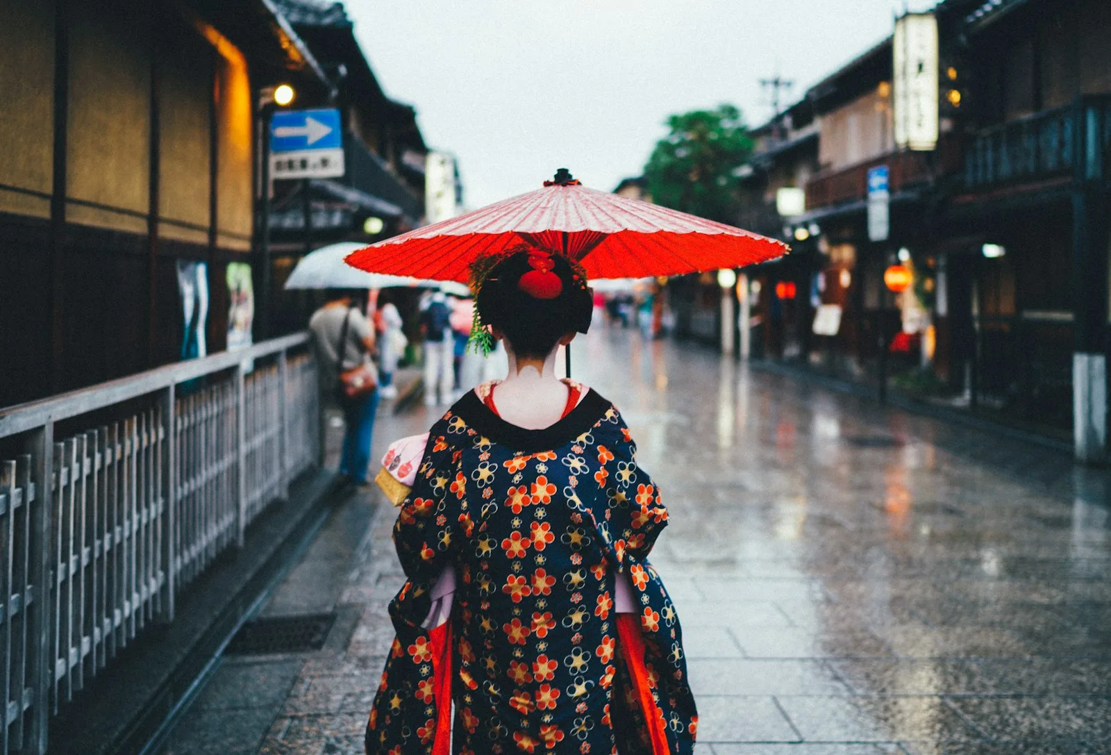 A woman with a red paper umbrella on a wet street