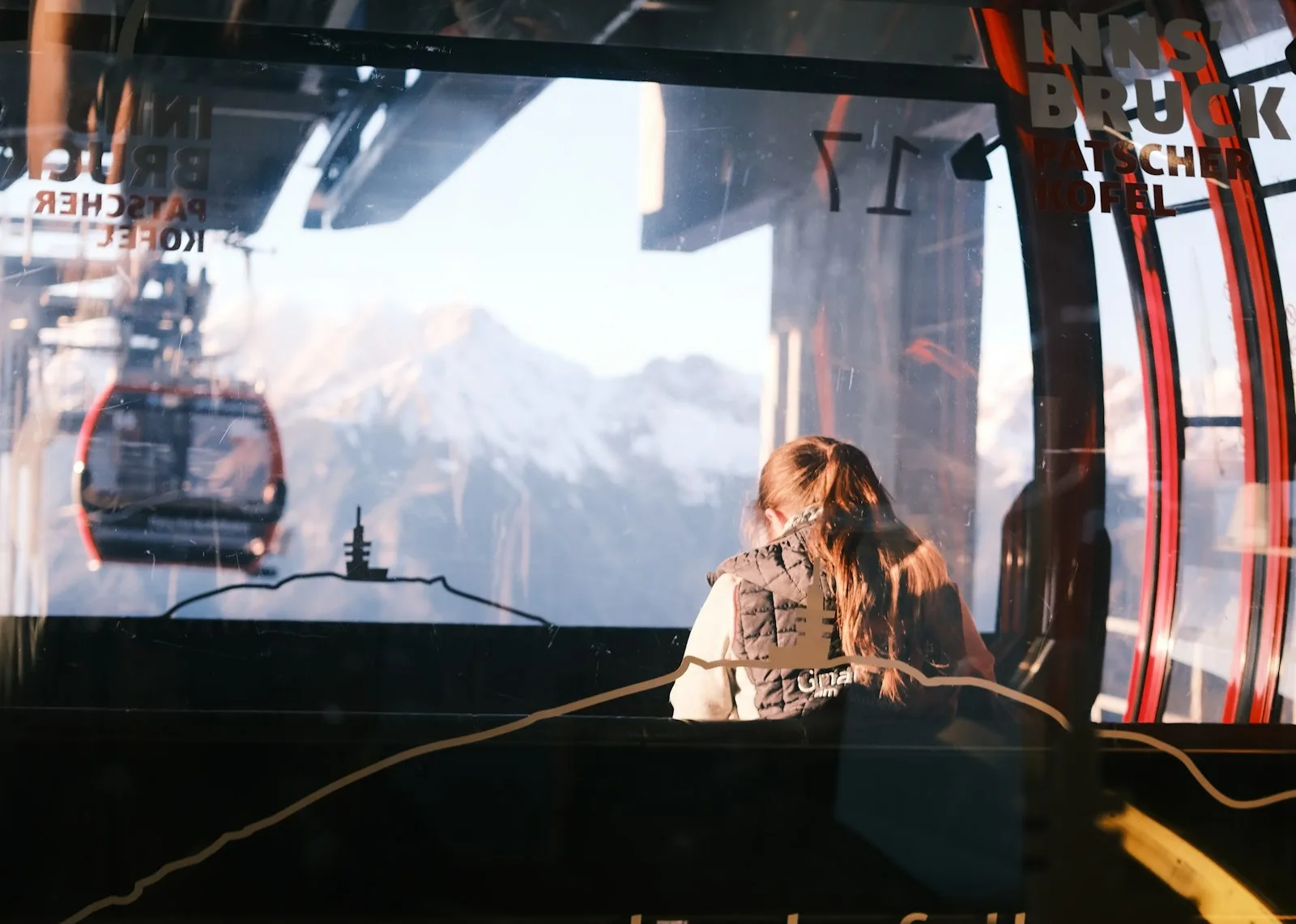 A woman looking out of a cable car at the mountains