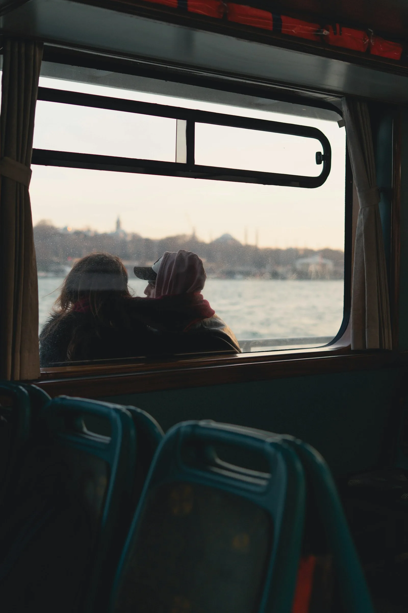 Two people at a ferry window, watching the city